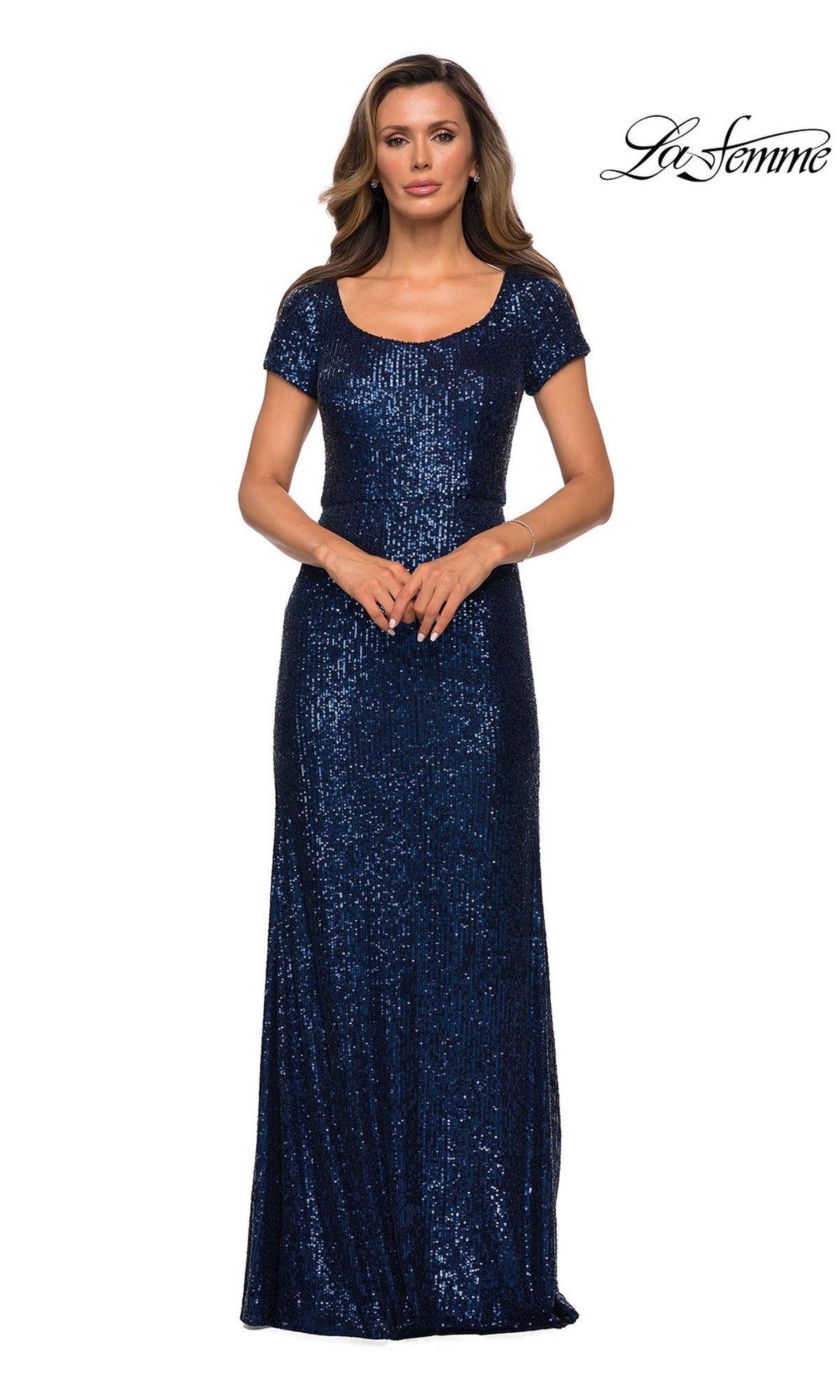 A woman wears a floor-length, navy blue sequin La Femme 27916 formal dress with short sleeves and a scoop neckline.